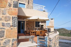 a house with a patio with a table and an umbrella at Villa Kimmi Natursteinhaus in Ierápetra
