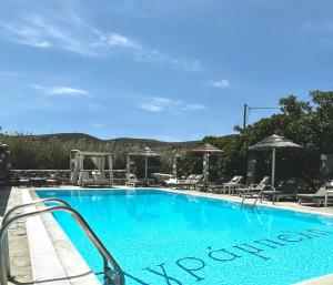 une grande piscine bleue avec des chaises et des parasols dans l'établissement Agrabeli Paros, à Náoussa