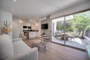 een woonkamer met een bank en een tafel met stoelen bij Le Greg - Terrasse - Parking - VCA in Cannes