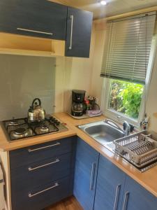 een keuken met een wastafel, een fornuis en een raam bij Camping Riva Bella - Mobil home Les4L in Ouistreham