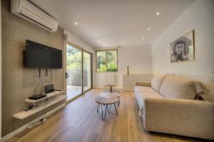 een woonkamer met een bank en een tv bij Le Greg - Terrasse - Parking - VCA in Cannes