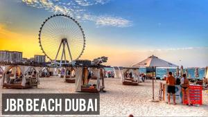 a beach with a ferris wheel and people on the beach at The W Jumeirah Beach in Dubai