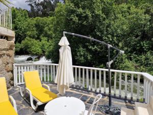 een patio met een tafel en stoelen en een parasol bij Dream corner by waterfalls, 20 min to Oporto in Parada