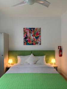 塔維拉的住宿－Ciao Tavira，卧室配有一张绿色的床,墙上挂有绘画作品