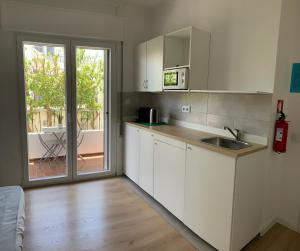 a kitchen with white cabinets and a sliding glass door at Ciao Tavira in Tavira