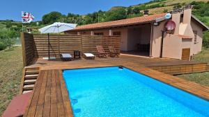 une piscine avec une terrasse en bois et une maison dans l'établissement Villa Marci con piscina privata a Nulvi (SS), à Nulvi