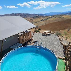 a swimming pool with a tent and a picnic table at Glamping Vive Tus Suenos -Equilibrio- Caminito del Rey in Alora
