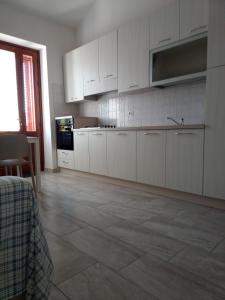 una cucina con armadietti bianchi e pavimento piastrellato di Appartamento B di Vico Martiri a Teulada