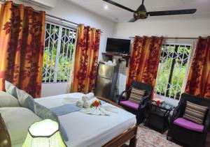 ein Wohnzimmer mit einem Sofa, Stühlen und Fenstern in der Unterkunft Buisson Guesthouse in La Digue