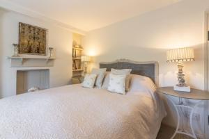 ein Schlafzimmer mit einem weißen Bett mit Kissen und einem Tisch in der Unterkunft Piper Cottage 2 in Holme next the Sea