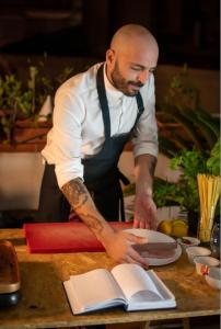 a man standing in a kitchen preparing food on a table at Maison Barriera - Luxury Suites - Salerno City Center in Salerno +15 photos