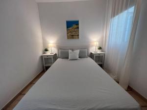 a large white bed in a white room with two tables at Casa Macken con piscina climatizada y jacuzzi in San Bartolomé