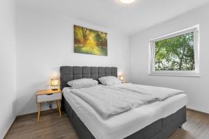 a white bedroom with a large bed and a window at Niewoh Ferienhaus Wiesenblick,Ammerland, Conneforde in Wiefelstede