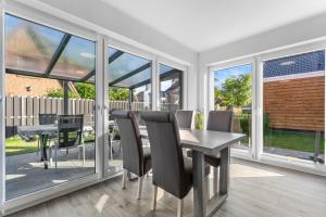 a dining room with a table and chairs and windows at Niewoh Ferienhaus Wiesenblick,Ammerland, Conneforde in Wiefelstede