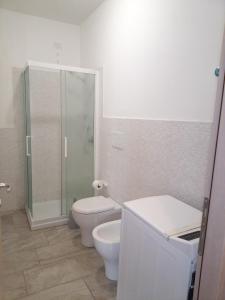 een witte badkamer met een toilet en een douche bij Appartamento A di Vico Martiri in Teulada