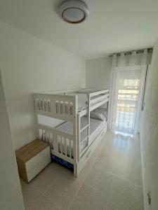 um quarto branco com 2 beliches e uma janela em Apartamento caribe em Oropesa del Mar
