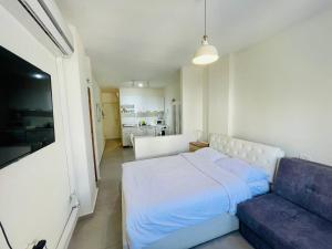 a bedroom with a white bed and a couch at Netanya Sea Studio in Netanya