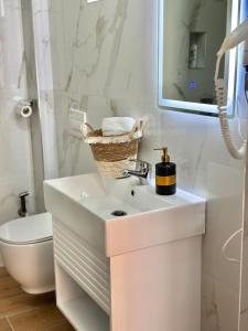 a white bathroom with a sink and a toilet at Hotel Imperial in Dhërmi