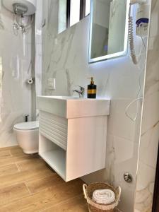 a white bathroom with a sink and a mirror at Hotel Imperial in Dhërmi