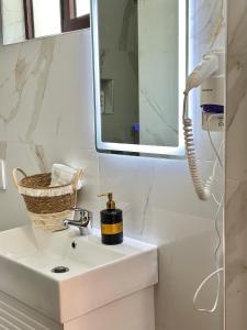 a white bathroom with a sink and a mirror at Hotel Imperial in Dhërmi