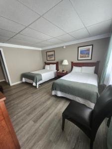 um quarto de hotel com duas camas e uma cadeira em The Cove Motel & Restaurant em Aulds Cove