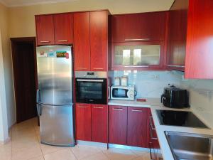 cocina con armarios rojos y nevera de acero inoxidable en Pazinos/Neveli Cottage en Galangádhos