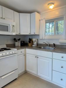 a white kitchen with white cabinets and a sink at The Even'tide in Wellfleet
