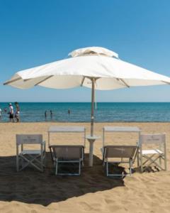 una mesa y sillas bajo una sombrilla en la playa en SoleeMare Barletta, en Barletta