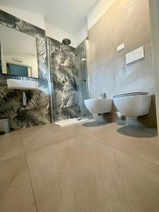 ein Badezimmer mit einem Waschbecken, einem WC und einem Spiegel in der Unterkunft Hotel Giardino in Breno