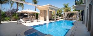 een zwembad met stoelen en een parasol bij Villa Inna in Caesarea