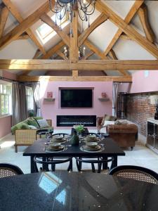 a living room with a table and a tv at Lynford Holiday Cottages nestled in the heart of Thetford Forest in Mundford