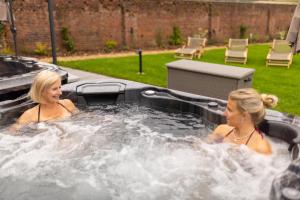 deux femmes dans un jacuzzi dans une cour dans l'établissement Cuckney House - Georgian Manor on a country estate - Sleeps 31, à Cuckney