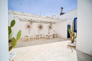 un patio avec des tables blanches, des chaises et des plantes dans l'établissement Salento Boutique Room B&B, à Sant'Isidoro
