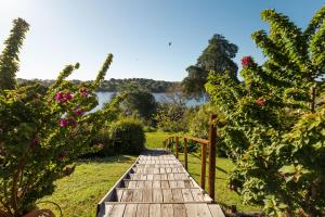 uma passagem de madeira num jardim com um lago ao fundo em Vale do Gaio Hotel em Torrão