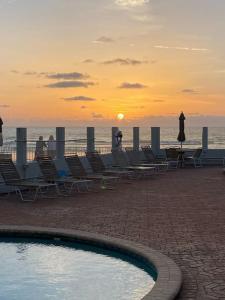 un gruppo di sedie e una piscina sulla spiaggia di SeaBliss, oceanfront 1st floor cozy condo a Daytona Beach