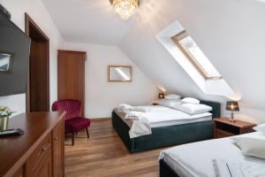 - une chambre mansardée avec 2 lits et une chaise dans l'établissement Pałacyk, à Międzywodzie