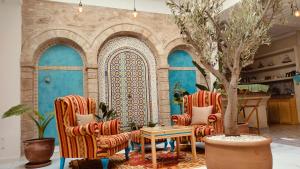 a living room with two chairs and a tree at Riad Al Manara in Essaouira