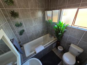 a bathroom with a tub and a toilet and a sink at Casa-Pel Guest Wing in Palatswe