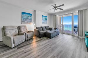 a living room with two chairs and a couch and a ceiling fan at Ocean Reef 904 by Emerald Coast Retreats in Panama City Beach