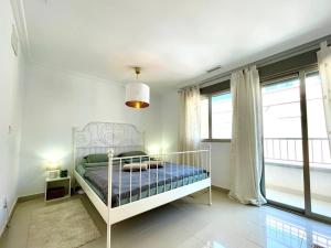 1 dormitorio con 1 cama blanca en una habitación con ventanas en Casa Ralphie, en Santa Pola