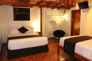 a hotel room with two beds and a chair at Epoca Iquitos in Iquitos