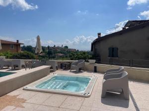 Un jacuzzi en un patio con sillas y mesas. en Dimora del Torchio, en Soiano del Lago