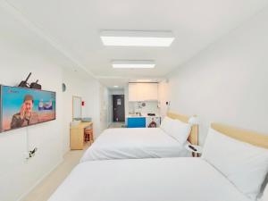 sypialnia z dwoma łóżkami i telewizorem na ścianie w obiekcie Ciel de Mer w Pusanie