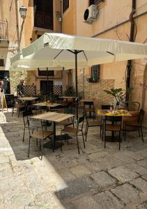 um pátio com mesas e cadeiras e um guarda-sol em Cortile dei Giusti - Combo Guesthouse em Palermo