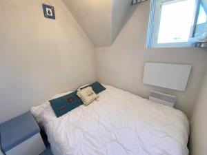 Un pequeño dormitorio con una cama blanca con una bolsa. en Gaelle, Studio proche plage, en Carnac