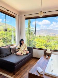 a woman sitting on a couch in front of a window at Pousada Belvedere da Serra in Serra do Cipo