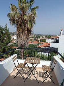 two chairs and a table on a balcony with a palm tree at Airport Loft , paiania in Paianía