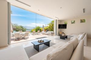 Una sala de estar con muebles blancos y una gran ventana. en Capitalia Tres Mares Beach Residences & Marina, en Puerto Vallarta