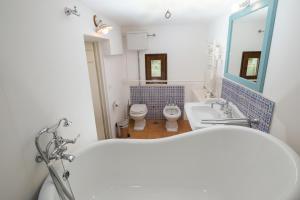 a bathroom with a tub and a toilet and a sink at Masseria Borgo Santuri in Ostuni