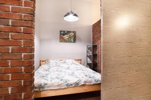 a bedroom with a bed and a brick wall at Dream Aparts - Lofty Scheiblera in Łódź